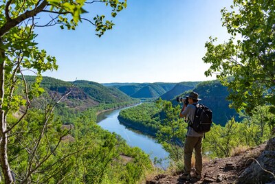 Man photographing river valley from cliff