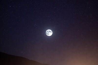 Full moon over starry sky and hills