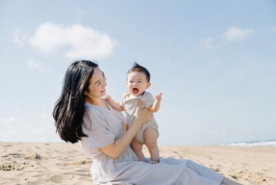 Asian mother holding smiling baby on beach