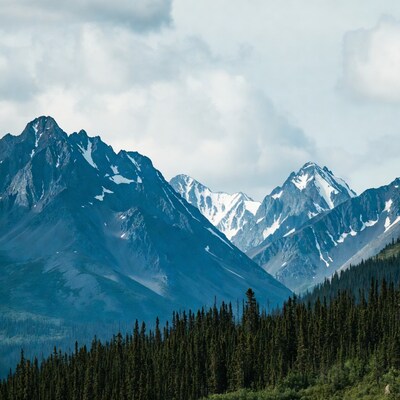Snowy Mountains with Forest Under Clouds