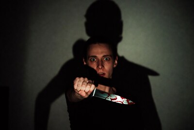 Man holding bloody knife with shadow