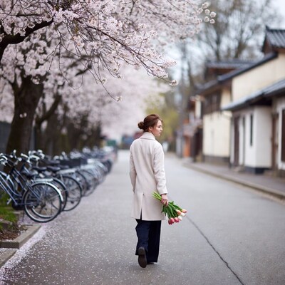 Asian woman walking with tulips under cherry blossoms