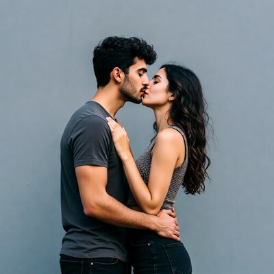 Couple kissing against gray wall