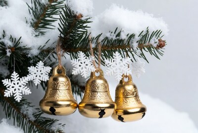 Gold bells hanging on snowy Christmas tree