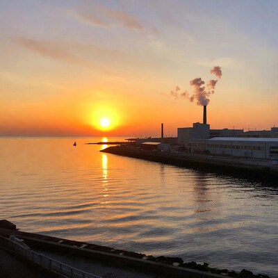 Sunset over industrial harbor with smokestack