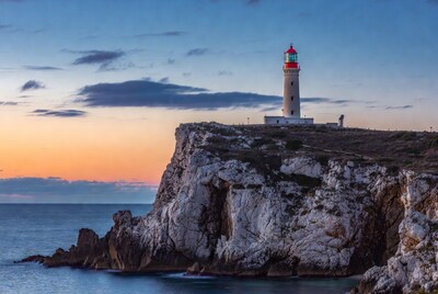 Lighthouse on cliff at sunset