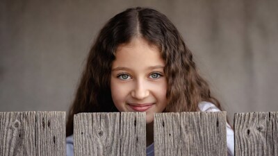 Girl peeking over wooden fence