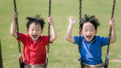 Asian boys swinging on playground swings