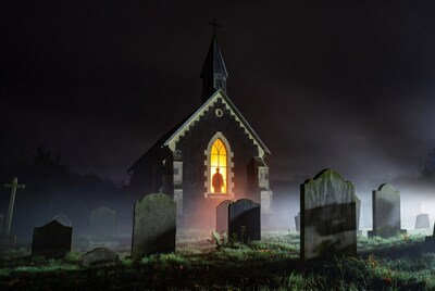 Gothic church in foggy graveyard at night
