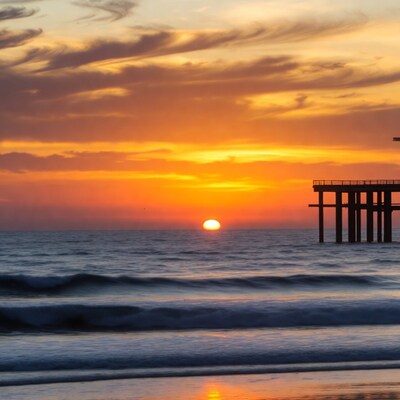 Sunset over pier and ocean waves