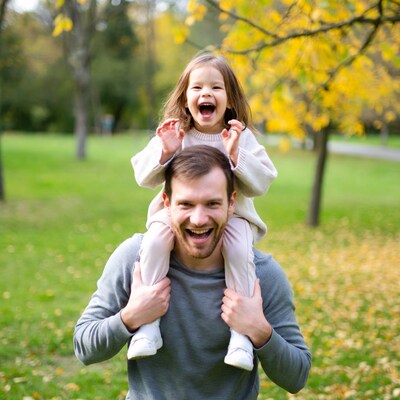 Father carrying laughing daughter on shoulders