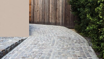 Curved cobblestone path by wooden fence