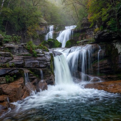 Majestic multi-tiered waterfall in misty forest