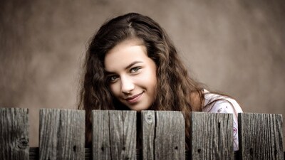 Woman peeking over wooden fence