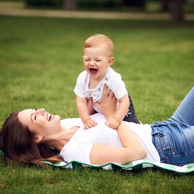 Mother and baby laughing on grass