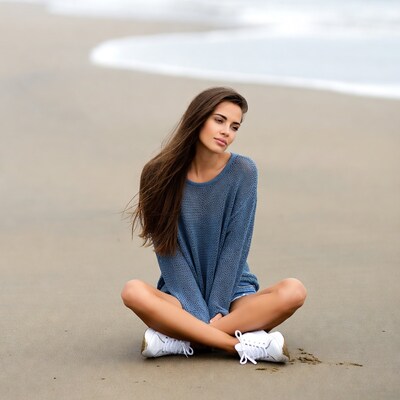 Woman sitting on beach in blue sweater