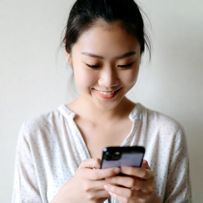 Asian woman smiling using smartphone