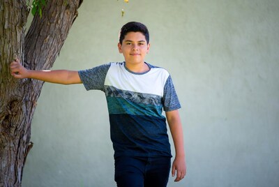 Latino boy leaning on tree