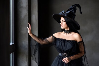 Woman in black witch hat by window