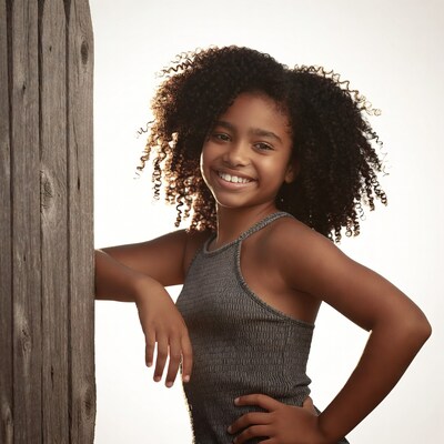 Smiling African-American girl leaning on wooden post
