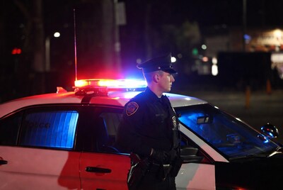 Police officer standing by patrol car
