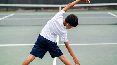 Asian boy stretching on tennis court