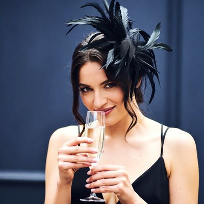 Woman sipping champagne with feather headpiece
