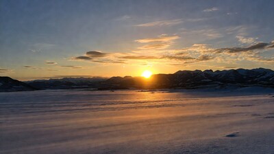 Sunset over snowy mountains and frozen lake