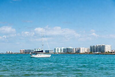 White sailboat on turquoise water with condos