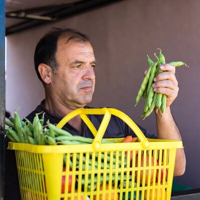 Man holding green beans at market stall