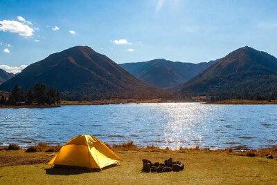 Yellow tent by lake with mountains