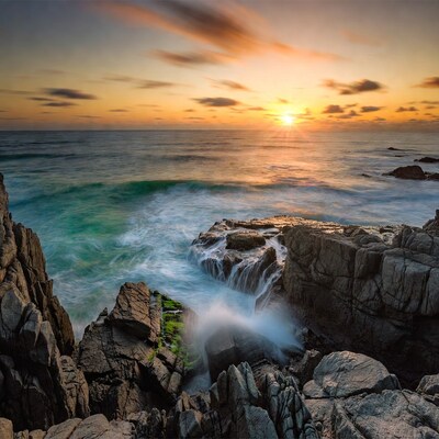 Sunset waves crashing on rocky coast