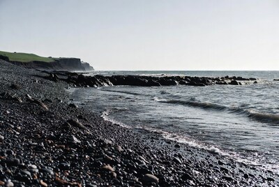 Black pebble beach with cliffs and ocean