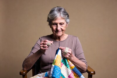 Elderly woman quilting colorful patchwork quilt