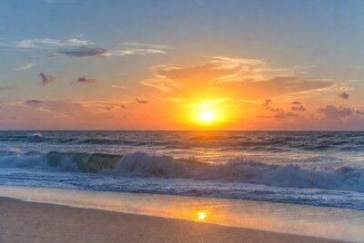 Sunset over ocean waves on beach