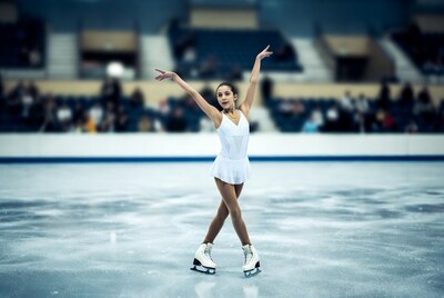Girl figure skating with arms raised