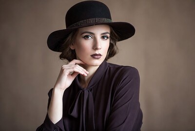 Woman in black hat touching chin