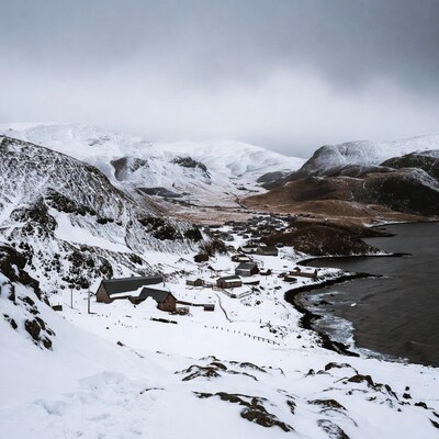 Snowy village by coastal mountains