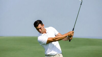 Man swinging golf club on green