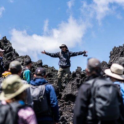 Man gesturing on volcanic rock with hikers