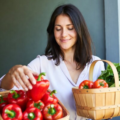 Woman holding red peppers and greens basket