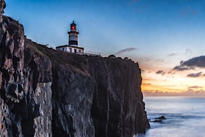 Lighthouse on rocky cliff at sunset