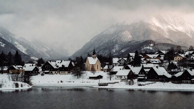 Snowy village church by lake mountains