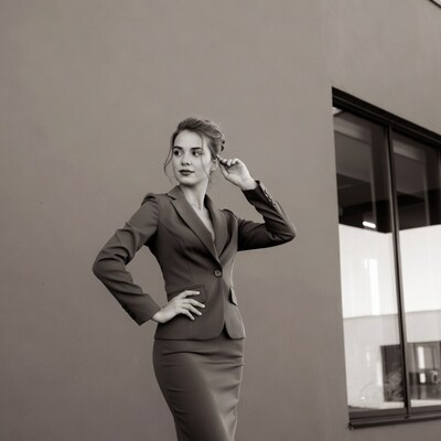 Woman in suit posing by building