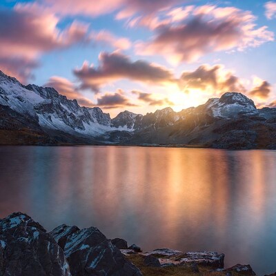 Sunrise over snowy mountains and lake