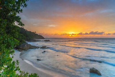 Tropical beach sunset with rocks and greenery