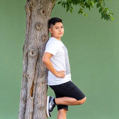 Latino boy leaning against tree