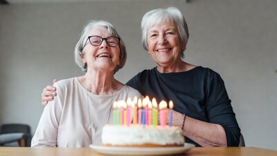 Two elderly women smiling at birthday cake
