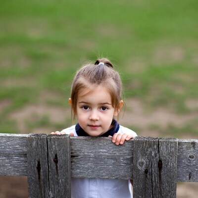 Girl peeking over wooden fence