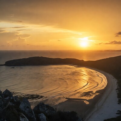 Sunset over curved beach and ocean